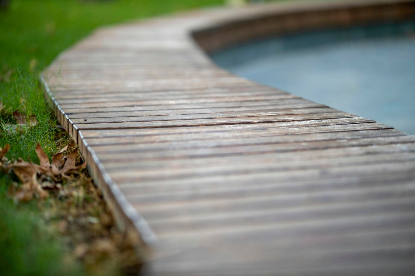Close-up of a wooden boardwalk curving along the edge of a tranquil pool.